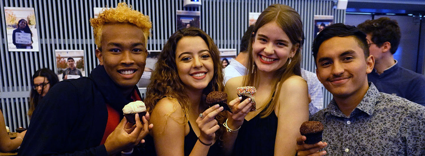 Four UC San Diego students at I-House smile and pose with cupcakes